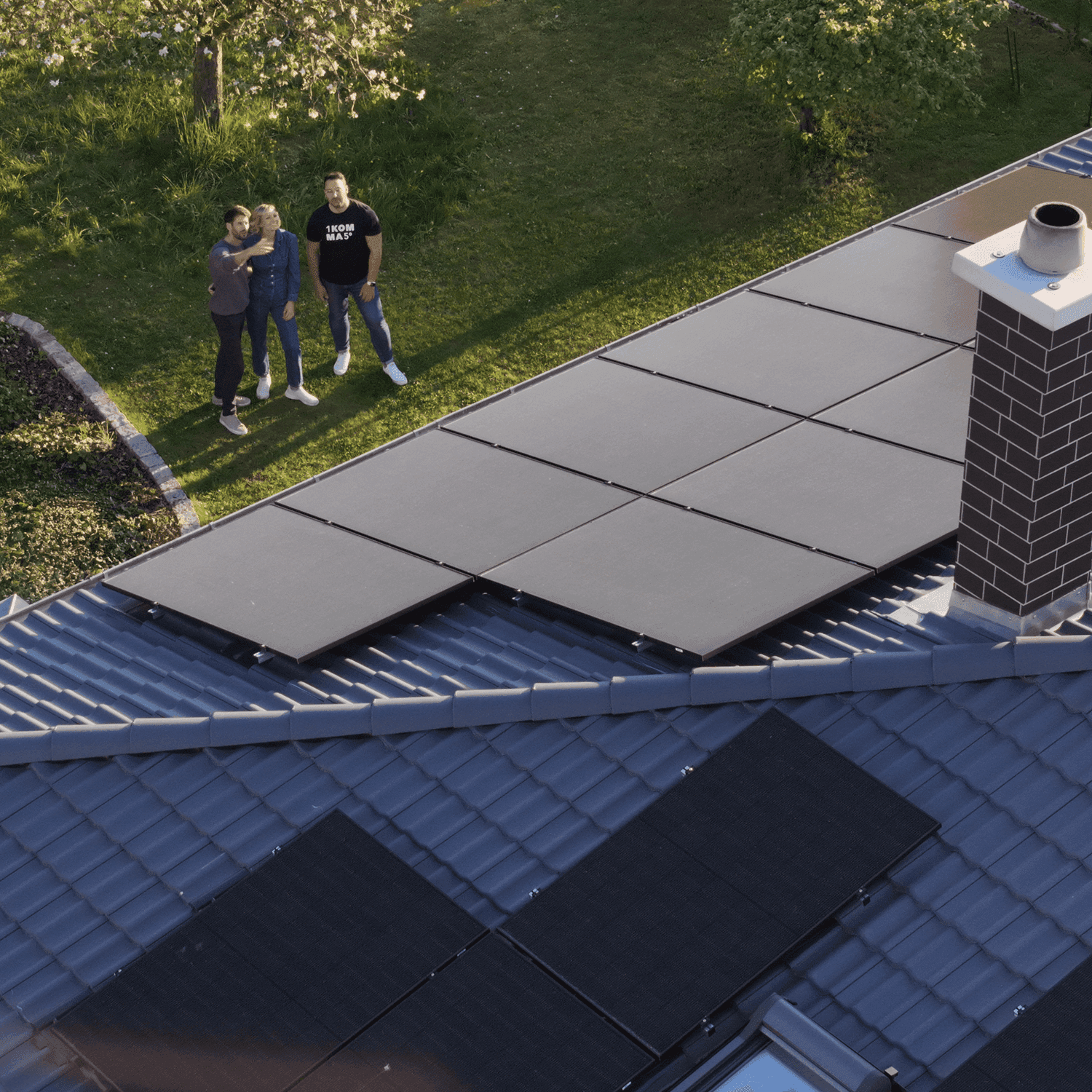 Kunden schauen mit Energie-Berater hoch auf ihr Dach mit Solaranlage