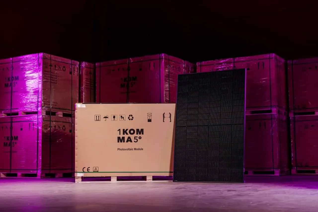 Ein Photovoltaik Modul steht aufrecht neben einem großen Karton mit der Aufschrift „1KOMMA5°“